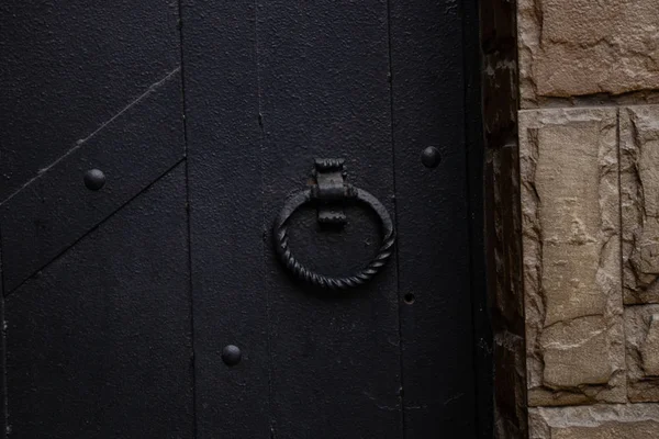 Round forged handle on an old black iron door close-up — 스톡 사진