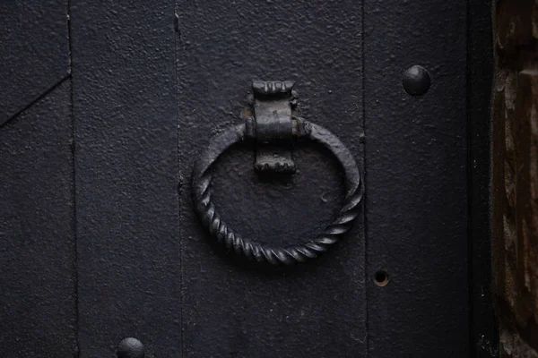 Rodada alça forjada em uma velha porta de ferro preto close-up — Fotografia de Stock