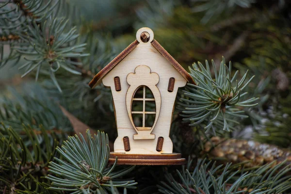 Malý dřevěný domek na větvích vánočního stromku — Stock fotografie