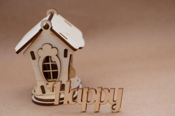 Une petite maison en bois se dresse sur la table et à côté de l'inscription heureuse en anglais de lettres en bois — Photo
