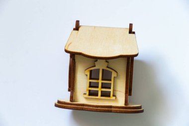 Beyaz arka planda küçük ahşap bir ev duruyor.