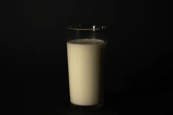 Glas mit Milch auf dunklem, isolierten Hintergrund — Stockfoto