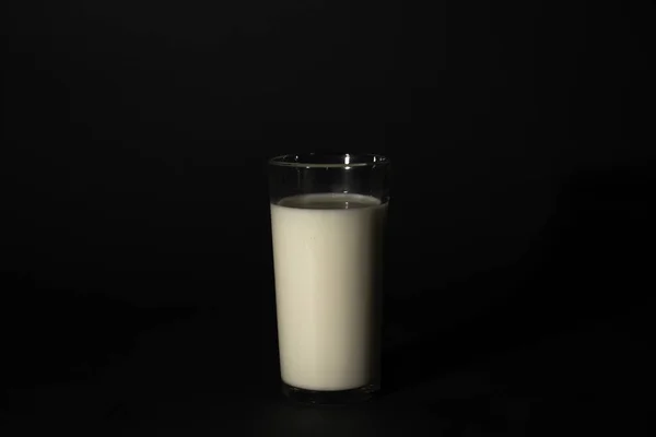 Glas met melk op een donkere geïsoleerde achtergrond — Stockfoto