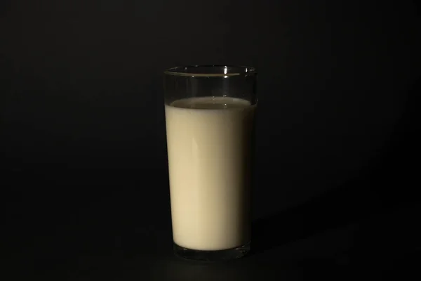 ミルク入りのガラスは暗い隔離された背景で — ストック写真