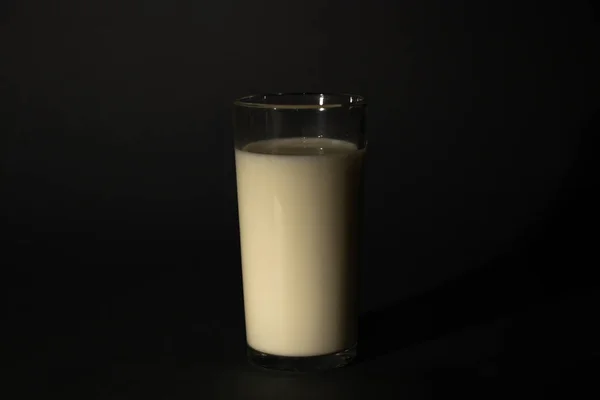 Vaso con leche sobre un fondo oscuro aislado —  Fotos de Stock