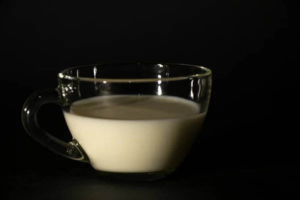 Vetro con latte su sfondo scuro isolato — Foto Stock