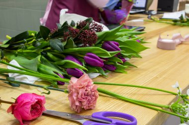 Çiçek kesme makası çiçekçide çiçeklerle dolu bir masada yatar.