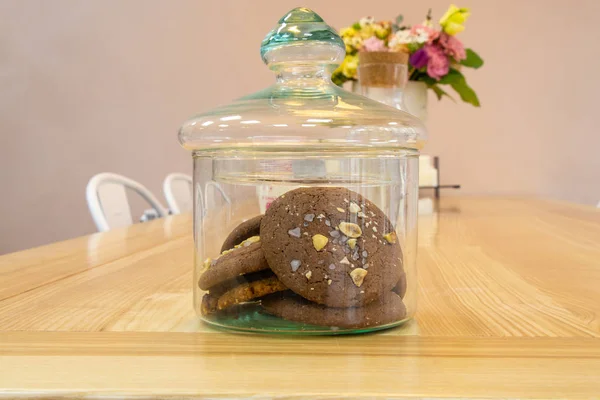 Стеклянная банка шоколадного печенья стоит на столе — стоковое фото