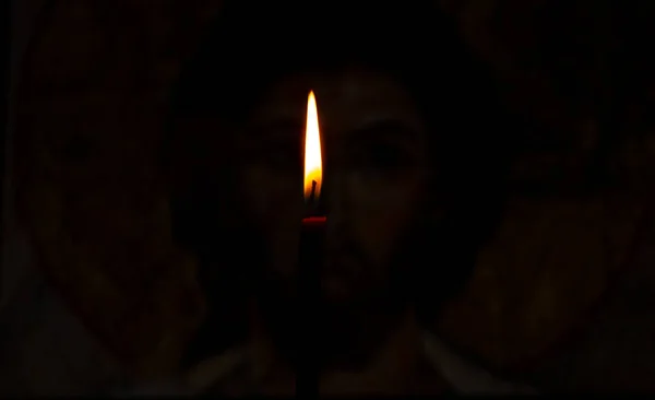 La vela encendida ilumina el icono de Jesucristo en la oscuridad —  Fotos de Stock
