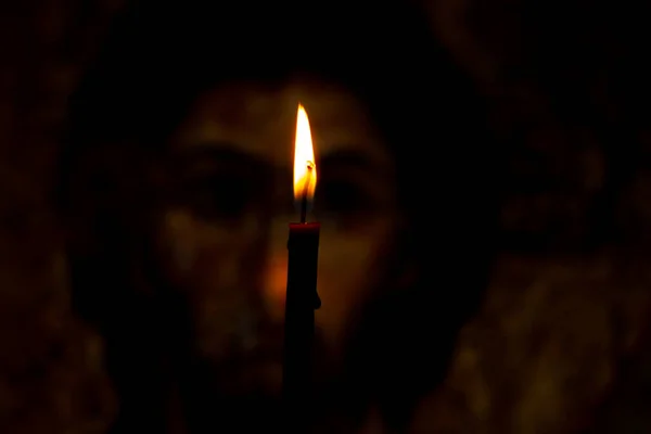 Paląca się świeca oświetla ikonę Jezusa Chrystusa w ciemności — Zdjęcie stockowe