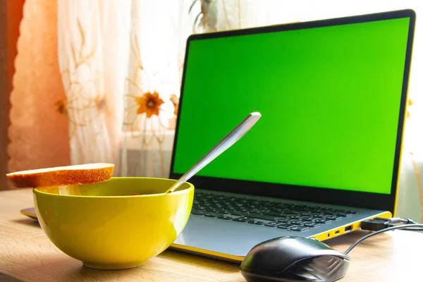靠窗房间的桌上放着一台装有绿色屏风和一盘食物的笔记本电脑 — 图库照片