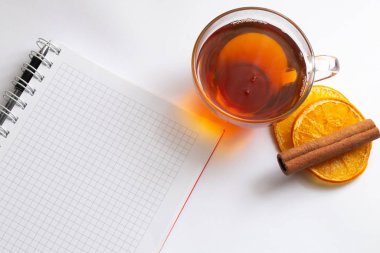 Beyaz arka planda bir fincan sıcak çay ve defter.