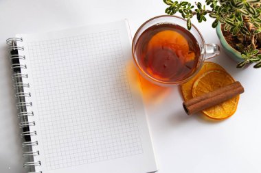 Beyaz arka planda bir fincan sıcak çay ve defter.