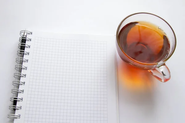 Notizbuch und Tasse heißen Tee auf weißem Hintergrund — Stockfoto