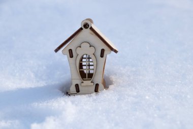children's little wooden house stands on the snow in the afternoon on the street