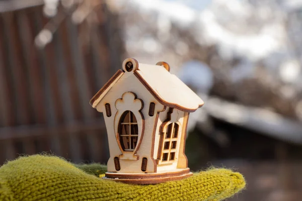 Malý dřevěný domek v rukou dívky v zimě na ulici — Stock fotografie