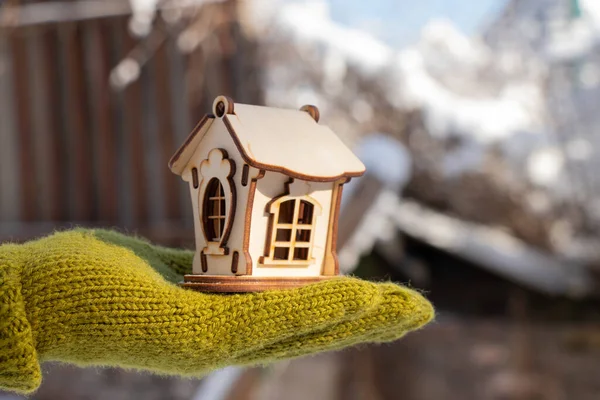 Una pequeña casa de madera en las manos de una niña en el invierno en la calle — Foto de Stock