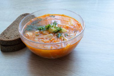 a plate with borsch and bread stands on a table in the daylight