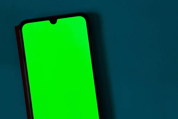 Érintőképernyős telefon zöld képernyővel, sötét háttérrel — Stock Fotó