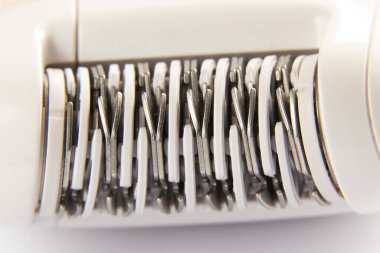 İzole bir arka planda vücut makro fotoğrafındaki kılları çıkarmak için elektrikli epilatör.