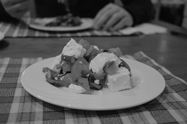 Ensalada con verduras y queso en un plato blanco por la noche en un restaurante en la cena —  Fotos de Stock