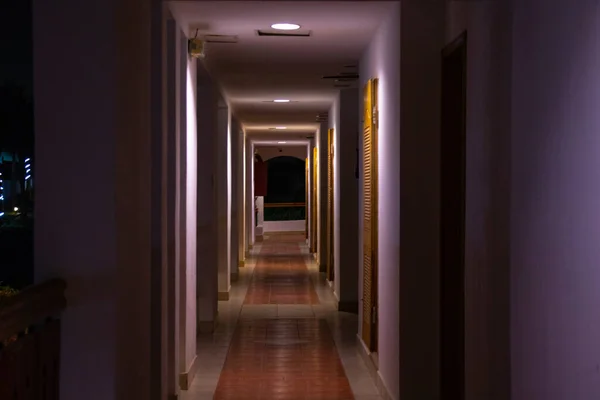 Largo corredor recto de un hotel hotel con iluminación oscura —  Fotos de Stock