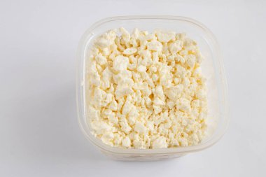 Beyaz arka planda beyaz bir kasede ekşi sütlü süzme peynir.