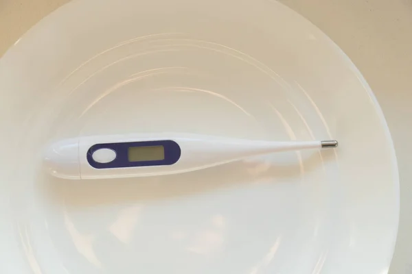 Ηλεκτρονικό Θερμόμετρο Βρίσκεται Ένα Λευκό Πιάτο Στο Τραπέζι — Φωτογραφία Αρχείου