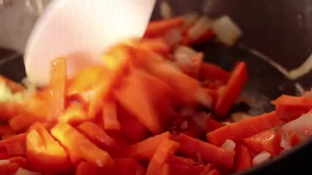 用勺子把洋葱和胡萝卜放在不粘的锅里煎 — 图库视频影像
