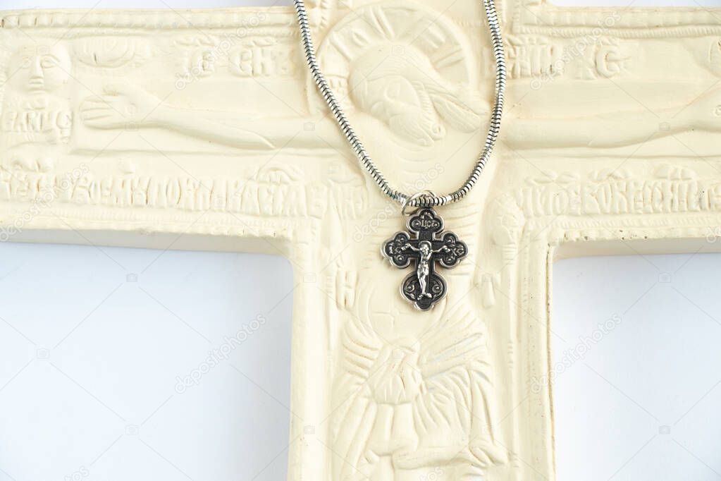 christian plaster cross and silver cross on chains on a white background close-up