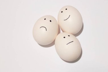 Beyaz bir yumurta, gözler ve ağız izole bir arka planda siyah bir keçeli kalemle çizilir.