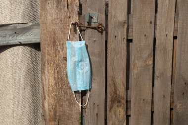 Tıbbi maske kancaya asılı. Ukrayna 'da eski ahşap bir kapı.