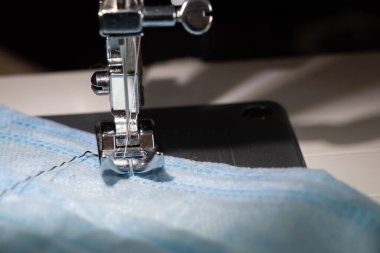 Yeni dikiş makinesi yakın çekim sırasında tıbbi maske dikiyor