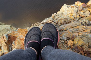 Ukrayna 'da taşlı bir taş ocağında, uçurumun kenarındaki bir kayanın üzerinde bacaklar duruyor.