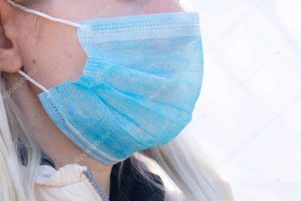 closeup of a young Ukrainian woman in a medical mask on her face during the pandemic outdoors