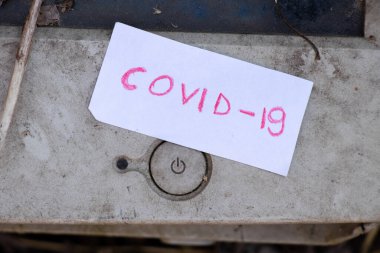 COVID-19 bir kağıt parçasına yazılır ve bir bilgisayarın kapatma düğmesinin yanında yatar