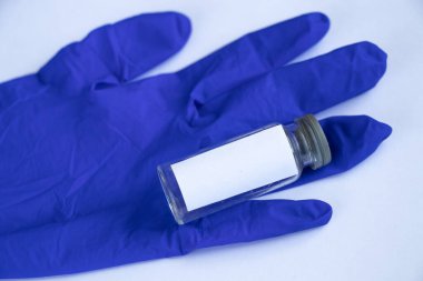 Üzerinde beyaz bir etiket ve tıbbi eldiven olan cam test tüpü.