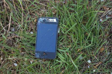 Ukrayna, Dnipro - Nisan 03, 2020. Eski bozuk bir iPhone 4 yeşil çimlerin üzerinde yatıyor.