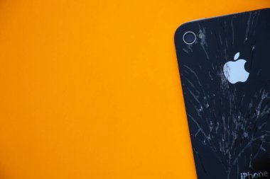 Ukrayna, Dnipro - Nisan 03, 2020. Eski kırık bir iPhone 4 turuncu bir arka planda yatıyor