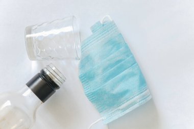 Tıbbi maske ve izole bir arka planda şişeden çıkan boğazlı bir bardak.