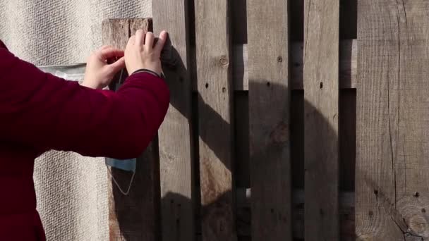 医療用マスクフックにかかってるウクライナの古い木製の門隔離期間中に通りに — ストック動画