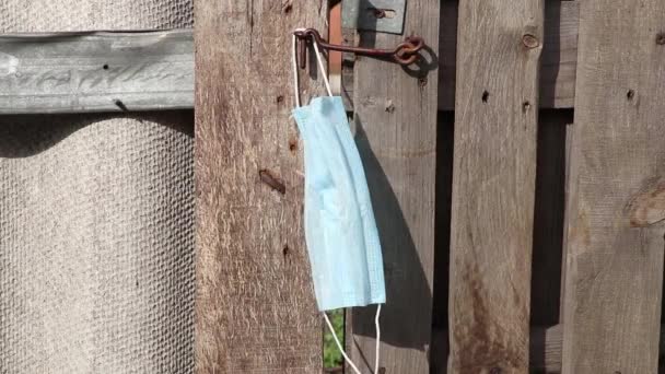 医療用マスクフックにかかってるウクライナの古い木製の門隔離期間中に通りに — ストック動画