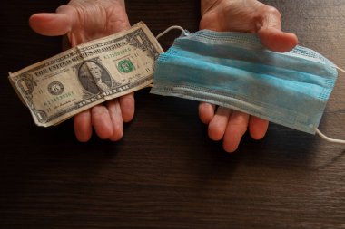 Tıbbi maske ve Amerikan doları yaşlı bir kadının ellerinde.