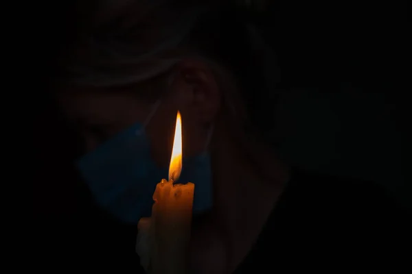 在黑暗的房间里 戴着医疗面罩 背靠着燃着的蜡烛的女孩 — 图库照片