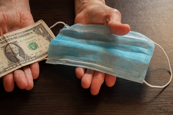 Tıbbi maske ve Amerikan doları yaşlı bir kadının ellerinde.