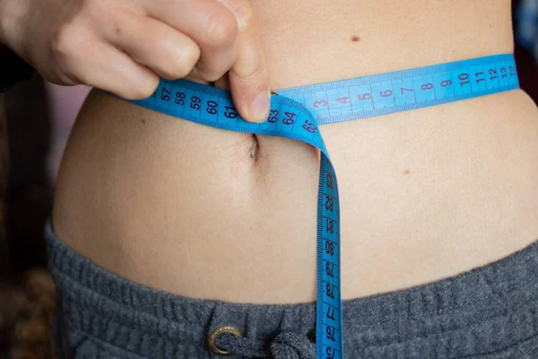 skinny belly of a young girl with a centimeter
