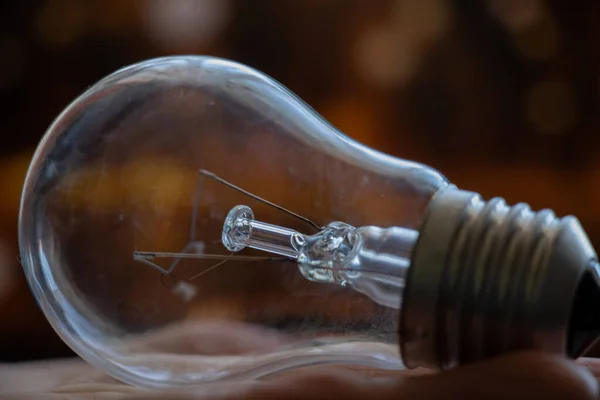old incandescent light bulb in hand on blurry dark background