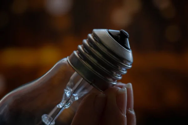 old incandescent light bulb in hand on blurry dark background