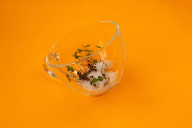 Filizlenmiş renkli tohumlar portakalın üzerindeki cam bardakta yatıyor.