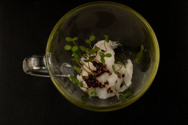 Renkli filizlenmiş tohumlar, siyah bir bardakta yatıyor.